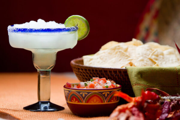 Traditional Mexican Chips, Salsa and Frozen Margarita with salt and lime on the rim of the glass on a table with Mexican decor.